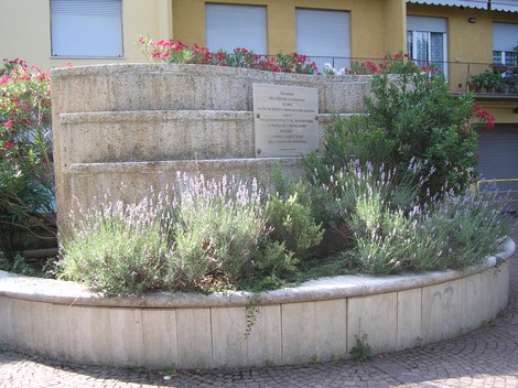 Monumento dedicato alla Liberazione, adornato da piante e fiori in un contesto urbano.
