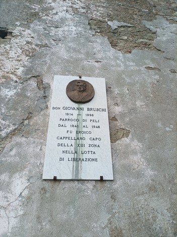 Lapide commemorativa di Don Giovanni Bruschi, con dettagli sulla sua vita e opera nella lotta di liberazione.