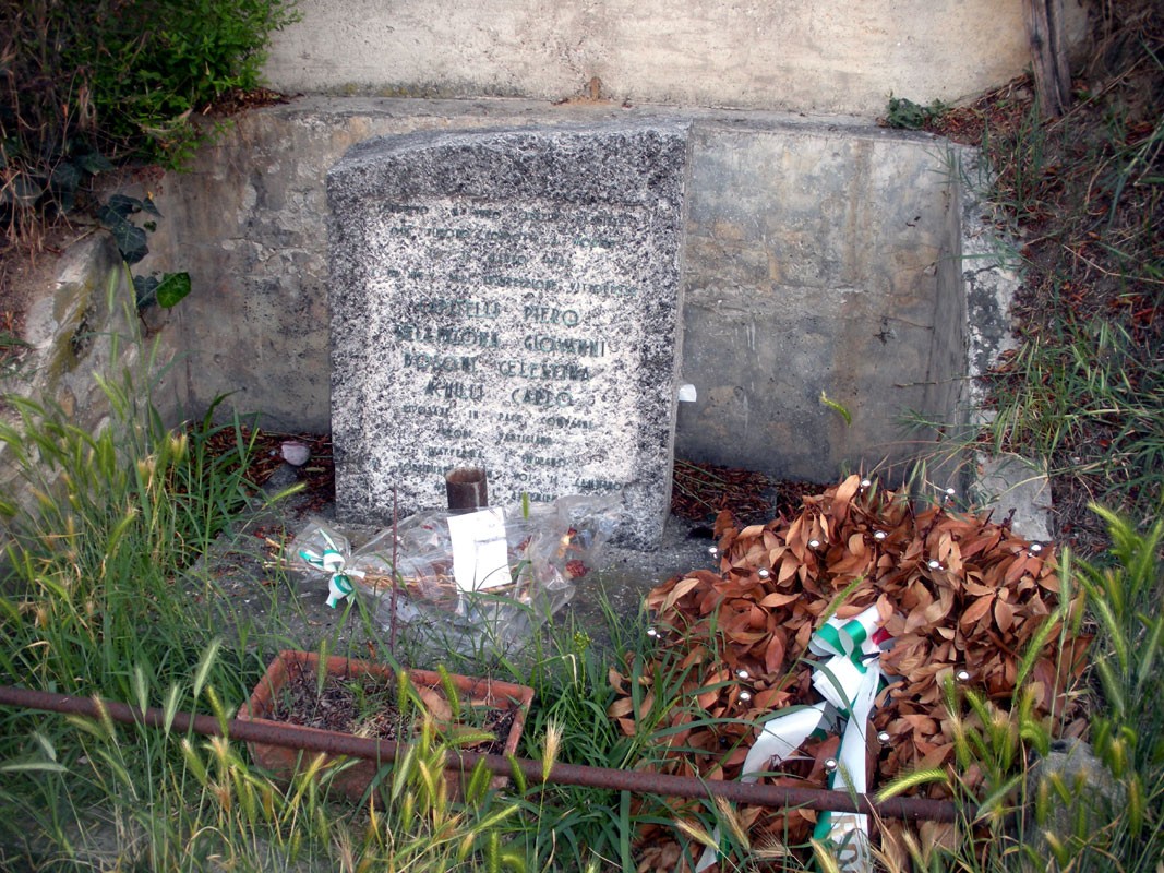 Lapide commemorativa ad Achilli, Bellinzona, con decorazioni floreali e atmosfera di ricordo.