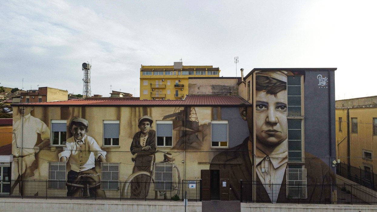 Murale commemorativo su un edificio, raffigurante figure storiche e culturali di Butera.