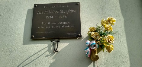 Targa commemorativa a Schölzel con decorazioni floreali, dedicata a un individuo e al suo coraggio.