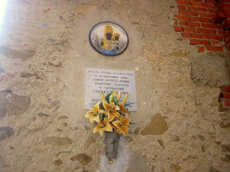 Lapide commemorativa a Borsetti con decorazioni floreali su una parete di pietra.