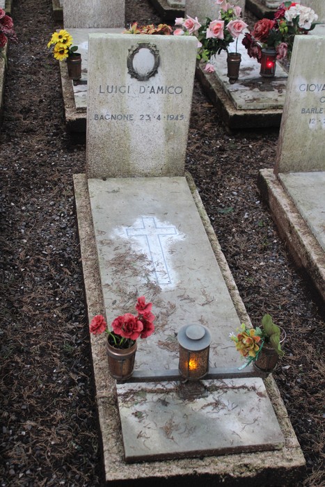 Tomba di Luigi D'Amico con fiori e lampada, commemorando i caduti per la Libertà. Atmosfera di rispetto e memoria.
