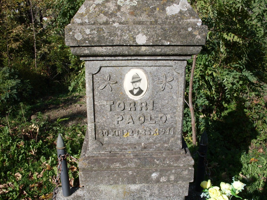 Cippo commemorativo dedicato a Paolo Torri, circondato da vegetazione.