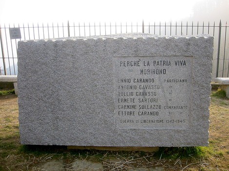Monumento in pietra dedicato ai caduti per la Libertà, con nomi di partigiani e date di guerra.