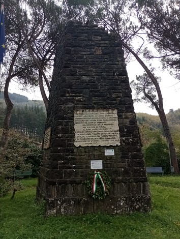 Monumento alla Resistenza, commemorazione scolpita nel granito in un'area verde, circondato da alberi.