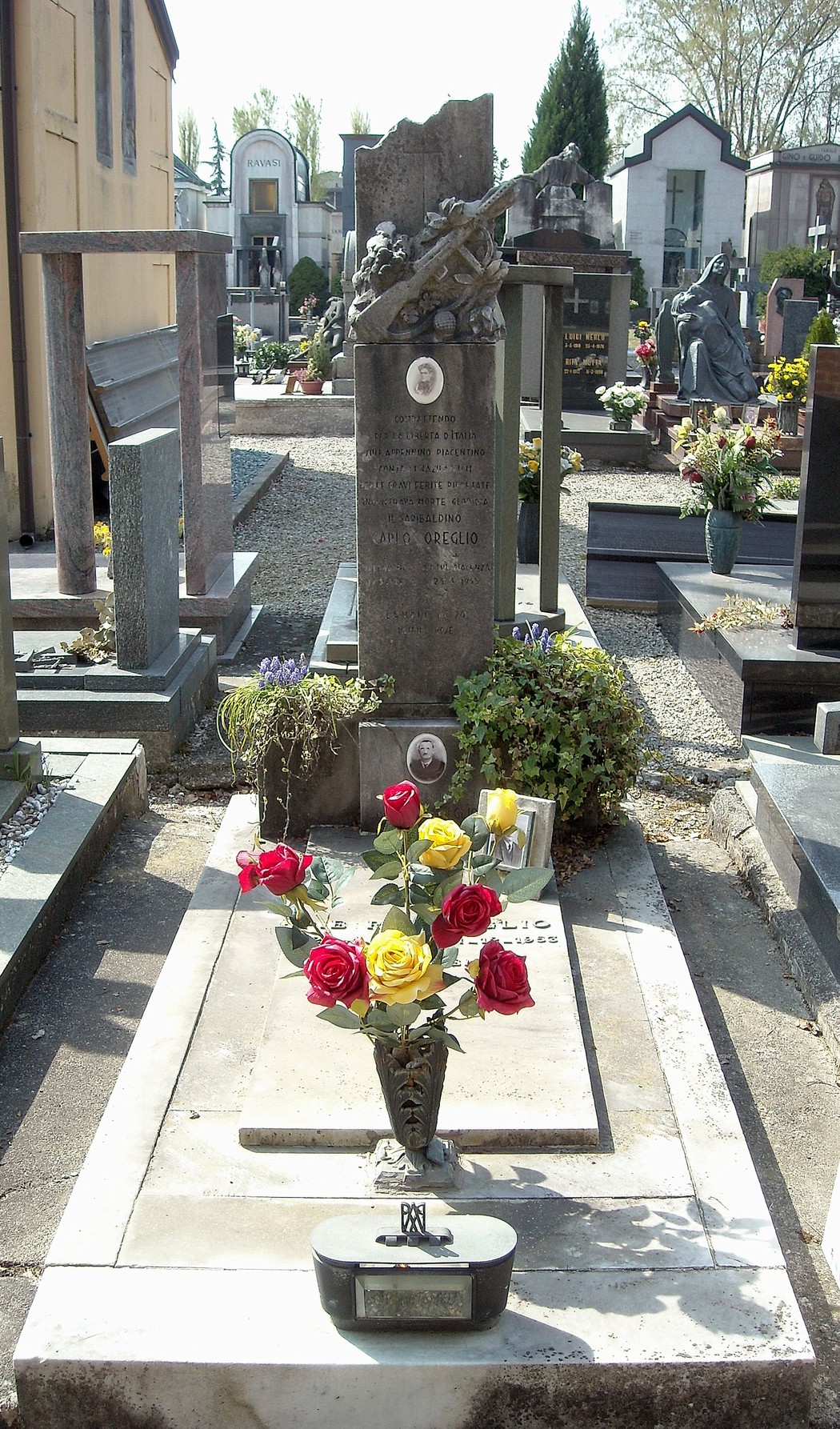 Tomba della Famiglia Oreglio con fiori colorati e decorazioni, all'interno di un cimitero ordinato.