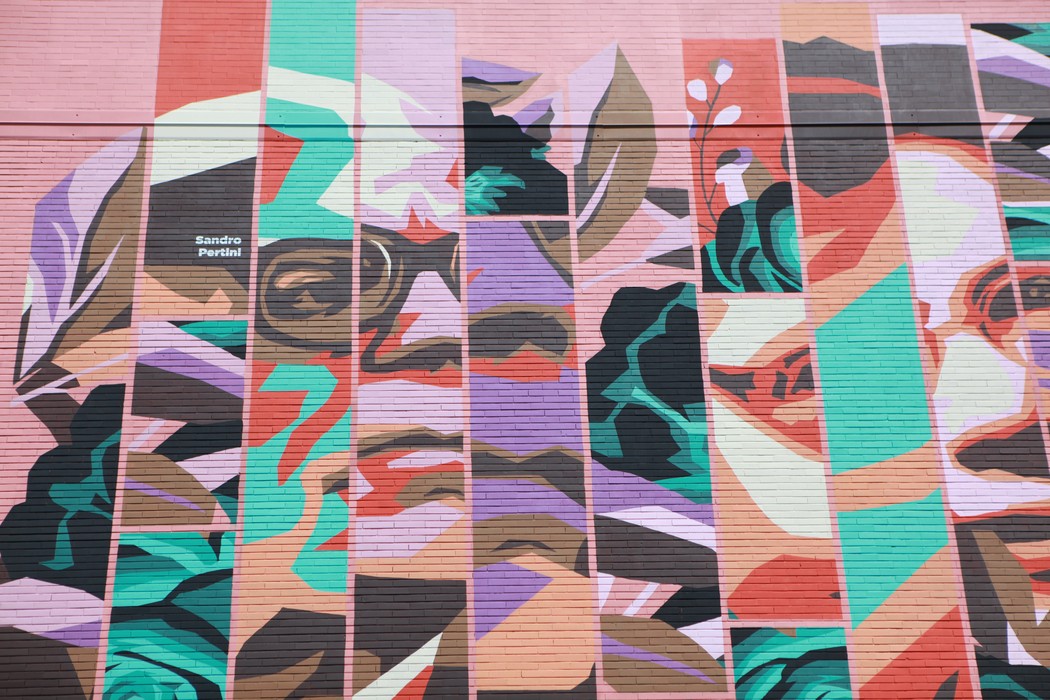 Murale colorato dedicato agli antifascisti, con volti stilizzati e dettagli floreali.