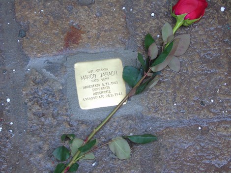 Pietra d'inciampo dedicata a Marco Jarach, con una rosa rossa posata accanto, in memoria della sua storia.