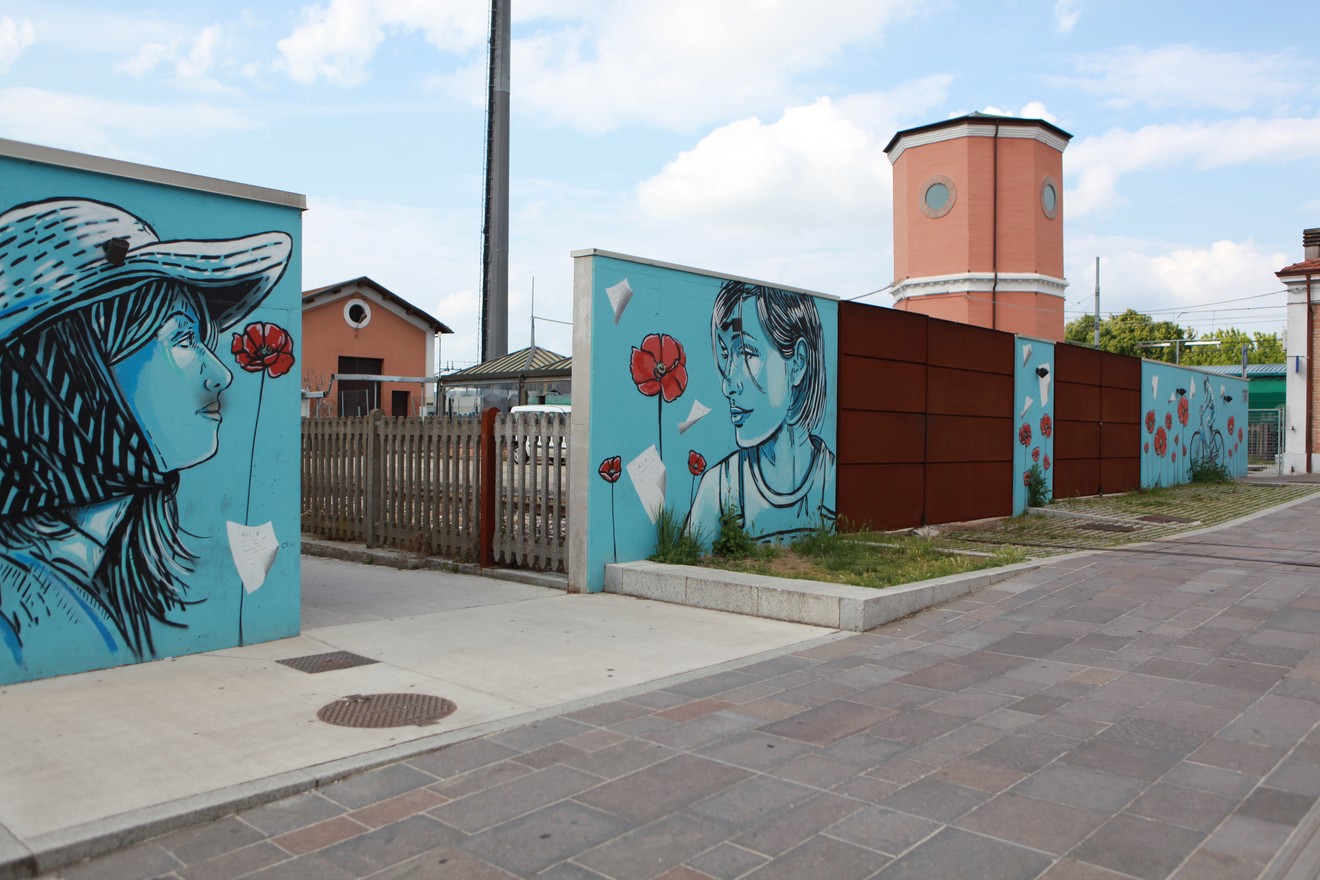 Murales colorato che rappresenta volti di persone con papaveri rossi su sfondo azzurro. Atmosfera vivace e suggestiva.