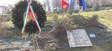Monumento commemorativo per l'eccidio del podere La Rossa, con corona d'alloro e bandiere.