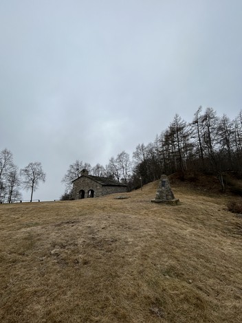 Monumento ai partigiani su una collina, circondato da alberi in un paesaggio grigio e invernale.