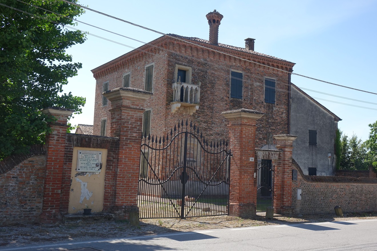 Villa storica a Cuccato con facciata in mattoni e cancello ornamentale.