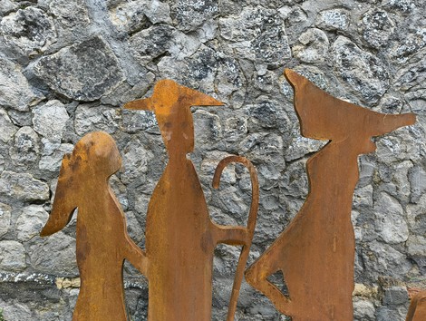 Statuette metalliche su uno sfondo di pietre, rappresentanti un gruppo che cammina.