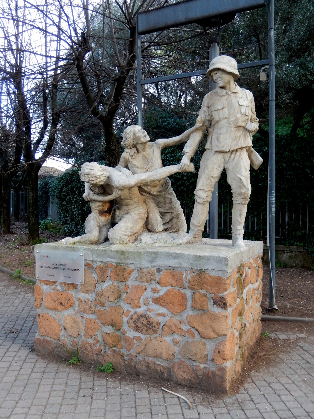 Monumento commemorativo con figure che rappresentano le vittime del rastrellamento del Quadraro, immerso nel verde.