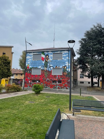 Murale commemorativo che omaggia le staffette partigiane, decorato con fiori rossi e simboli nazionali.