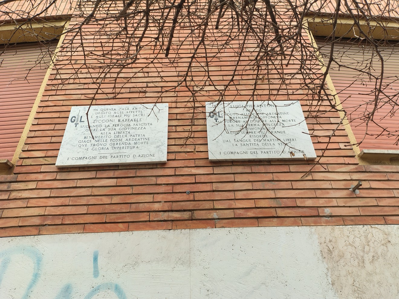 Lapidi commemorative di Zicconi e Pierantoni su una parete di mattoni a vista.