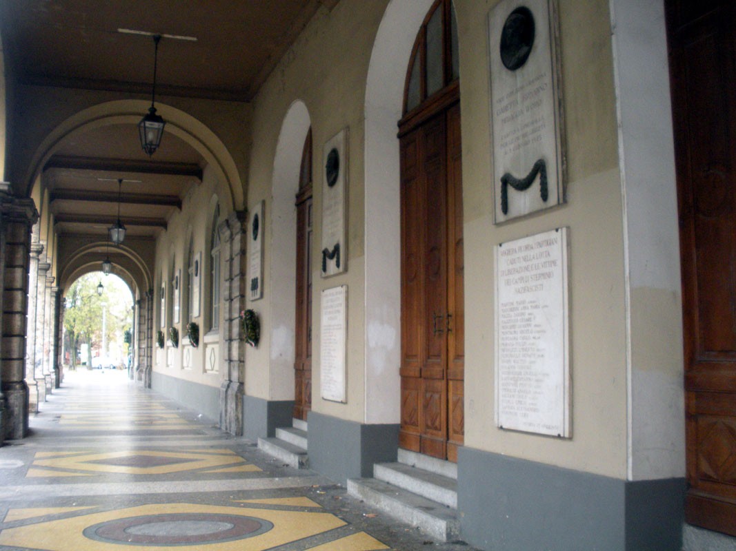 Lapide commemorativa ai caduti, situata sotto i portici di Voghera, con dettagli architettonici storici.