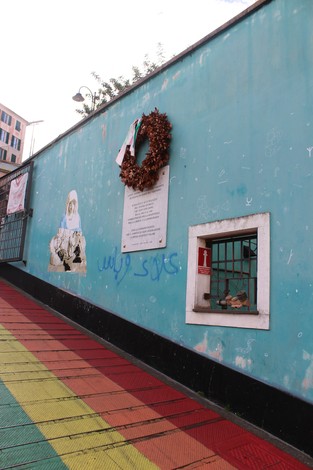 Lapide commemorativa dedicata agli antifascisti e partigiani, affiancata da decorazioni e un'apertura nel muro.