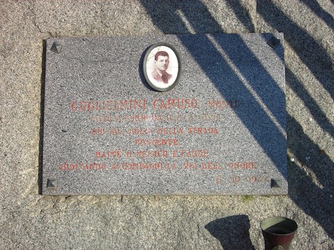 Cippo commemorativo in memoria di Guglielmini Caruso, con foto e iscrizione su pietra.