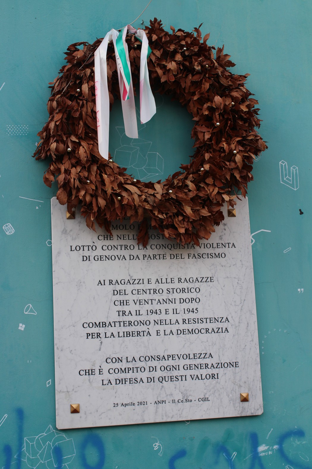 Lapide commemorativa dedicata agli antifascisti del '22 e ai partigiani, adornata da una corona di foglie.