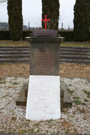 Monumento dedicato ai caduti, con croce rossa e lapidi commemorative, immerso in un'area verde.