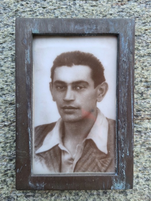 Immagine di una lapide con una foto in bianco e nero di un giovane uomo in abbigliamento classico.
