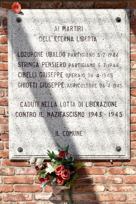 Monumento commemorativo in onore dei martiri della libertà, con una rosa e una dedica scolpita.