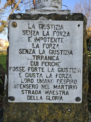 Cippo in pietra con iscrizioni dedicate a "Brambilla, Fava e Pezzali" in un contesto naturale.