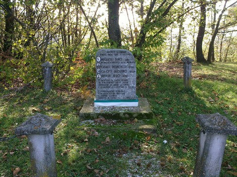 Cippo commemorativo in un bosco, circondato da alberi, in memoria di Casali, Casotti e Rinaldi.