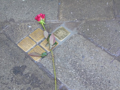 Pietre d'inciampo dedicate alla famiglia Melli - Mariani con una rosa posata accanto.