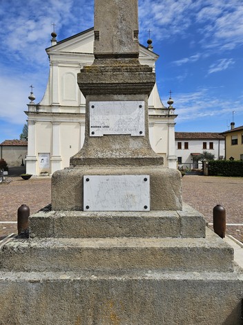 Monumento ai Caduti di Bosaro, situato in una piazza con una chiesa sullo sfondo e cielo blu.