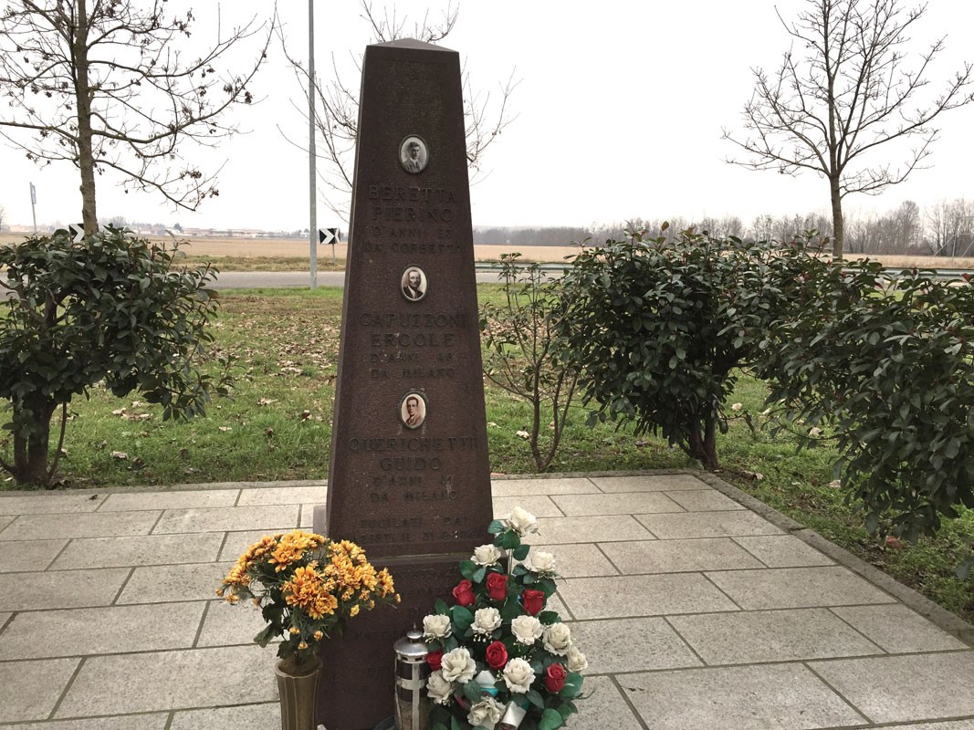 Monumento commemorativo per le vittime dell'eccidio di Torriano, con fiori e ritratti nel ricordo.