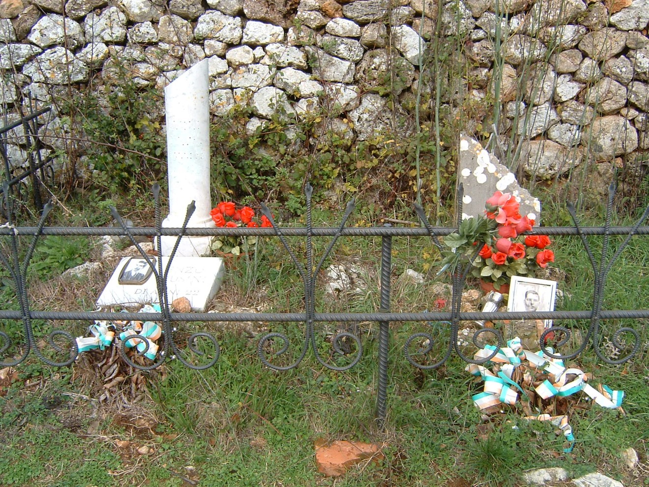 Cippi commemorativi ai caduti di Montemaggio, circondati da fiori e ricordi in un luogo di memoria.