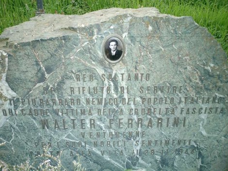 Cippo commemorativo dedicato a Walter Ferrarini, con un ritratto e incisi il suo nome e messaggi di ricordo.