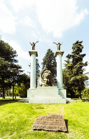 Monumento ai caduti di Suzzara, omaggio ai valorosi, circondato da alberi e verde. Simbolo di memoria e riconoscenza.