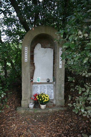Monumento dedicato alle vittime dell'eccidio di San Polo, immerso nel verde e adornato di fiori.