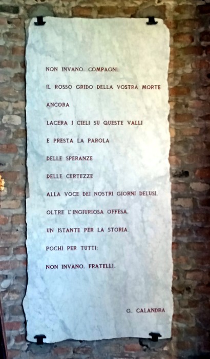 Il sacrario commemorativo con iscrizioni su una parete di pietra, simbolo di memoria e devozione.