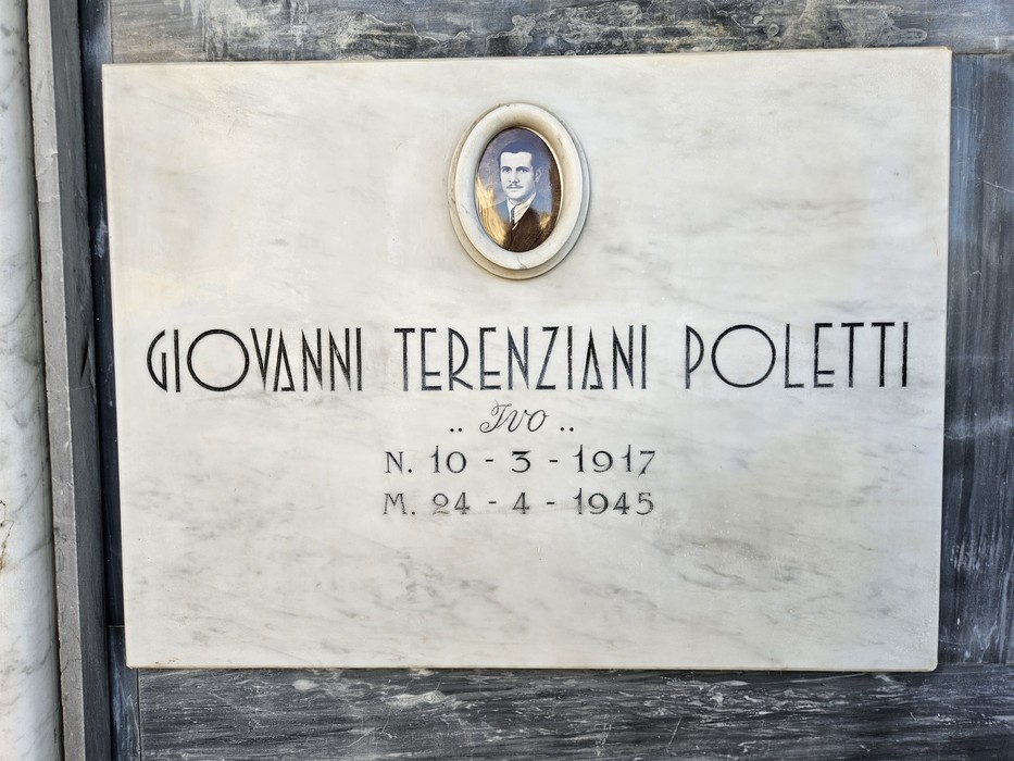 Lapide in marmo con ritratto ovale fotografico e iscrizione dedicata a un caduto.