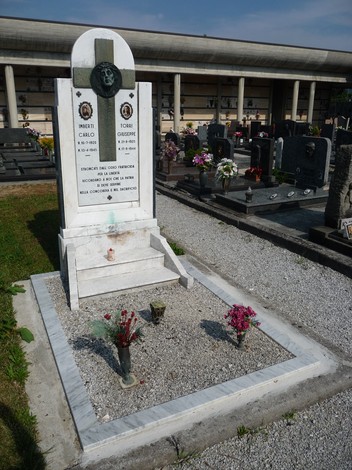 Monumento commemorativo con lapidi e decorazioni floreali in un cimitero, dedicato a Imberti e Torri.