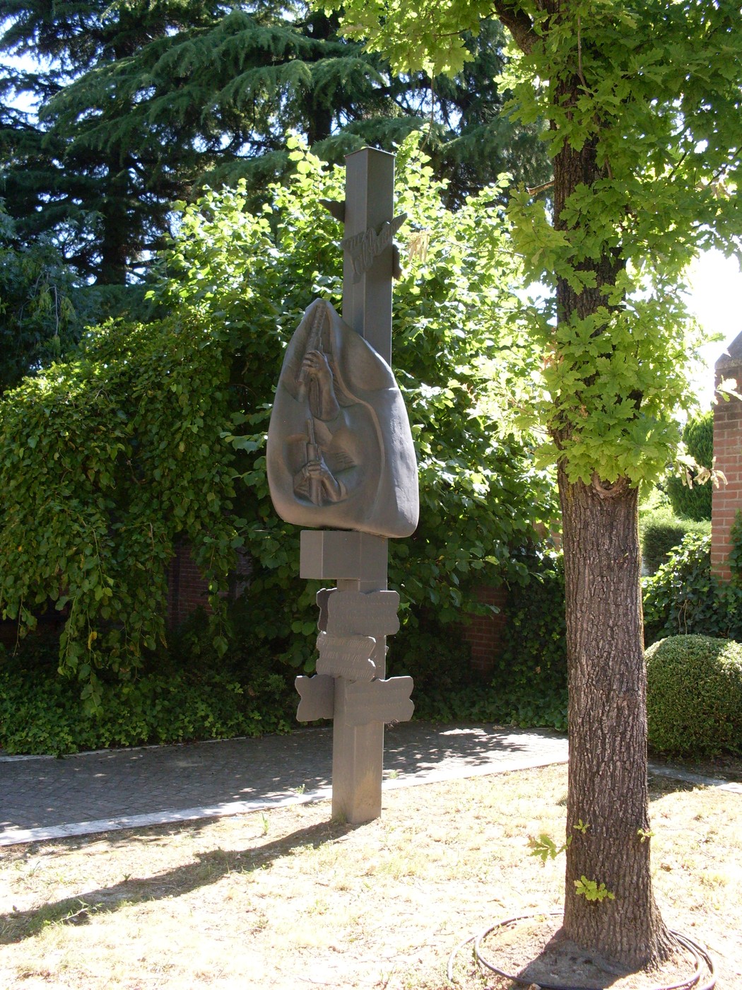 Monumento della Resistenza di Montecavolo, con scultura in metallo immersa nel verde di un giardino luminoso.