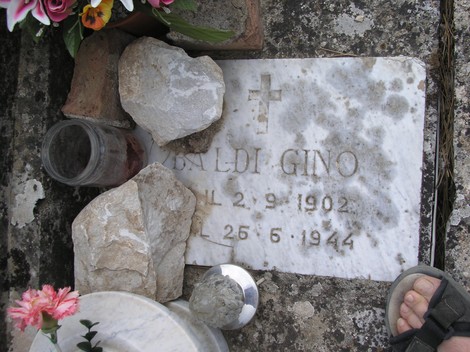 Targa commemorativa nel Sacrario dei partigiani, con fiori e pietre in ricordo dei caduti.