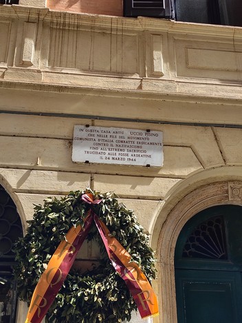 Lapide commemorativa a Pisino con una corona di alloro e un nastro, in ricordo di eventi storici.