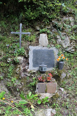 Lapide commemorativa decorata con fiori, situata in un contesto naturale, dedicata ai caduti per la Libertà di Vertova.