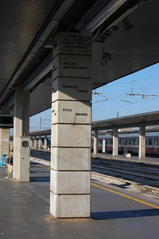 Monumento ai ferrovieri caduti per la libertà, situato in una stazione ferroviaria, con binari sullo sfondo.