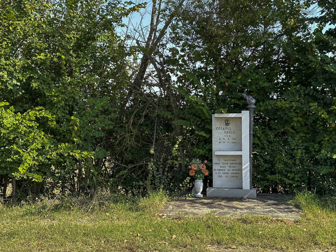 Monumento a Pavesi immerso nella natura, con fiori e vegetazione circostante.