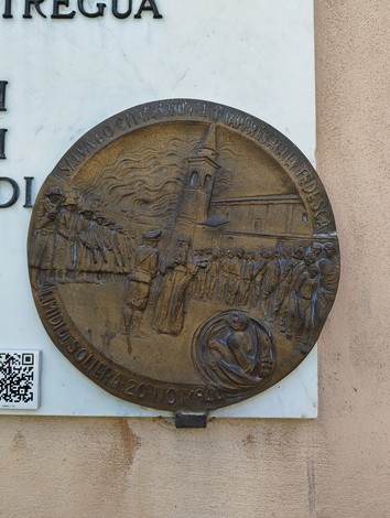 Lapide commemorativa per gli ostaggi liberati, con rilievo di figure e architettura storica.