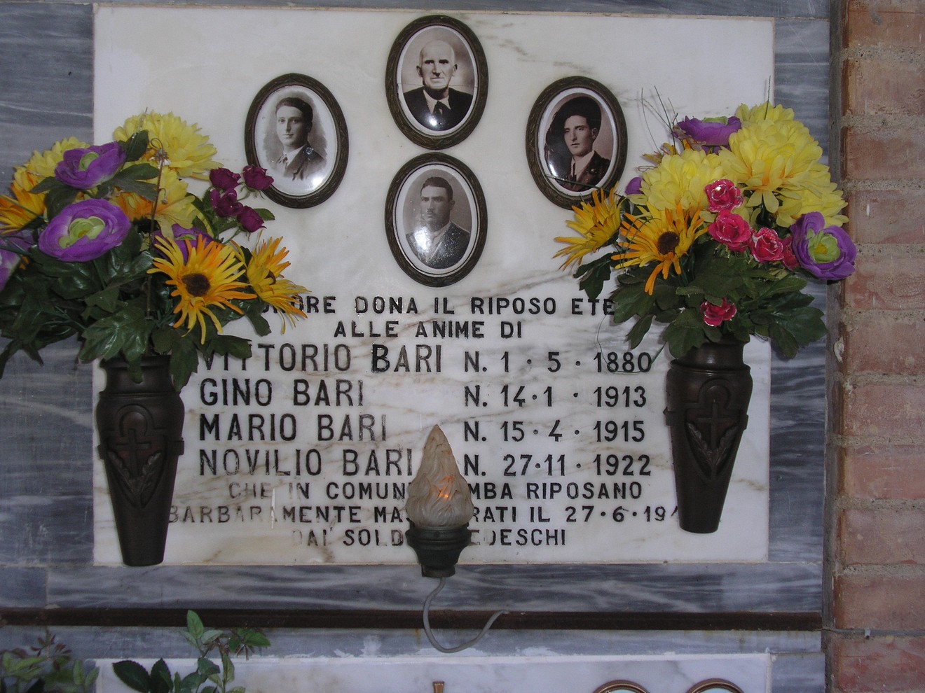 Sepolcro della famiglia Bari, decorato con fiori e ritratti, situato in un ambiente commemorativo.