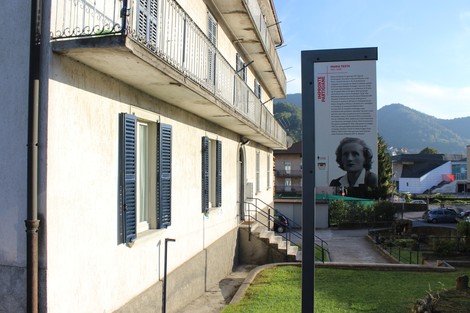 Impronta partigiana a Testa, con edificio storico e pannello informativo in un contesto naturale.