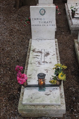 Tombe con fiori e una candela, dedicate ai caduti per la Libertà, in un luogo di commemorazione e rispetto.